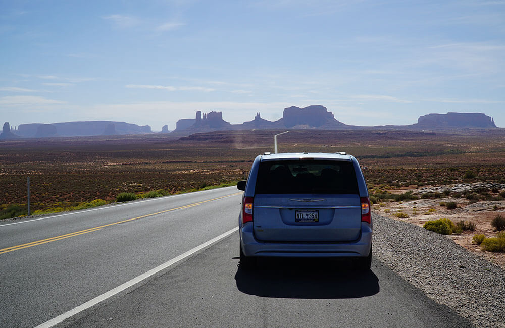 Our car with Monument Valley in the distance, near the Arizona-Utah border